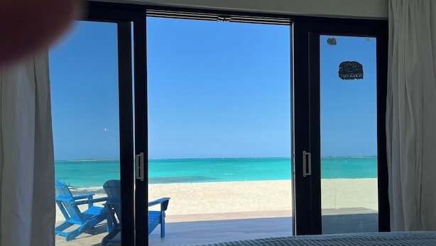A bedroom with a large sliding glass door leading to a beach view. - Steps From the Water on One of The Most Beautiful Beaches in Exuma! (Rokers Point Settlement)