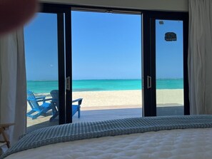 A bedroom with a large sliding glass door leading to a beach view. - Steps From the Water on One of The Most Beautiful Beaches in Exuma! (Rokers Point Settlement)