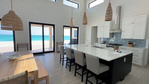 A modern kitchen with a large island, white cabinetry, and a view of the beach. - Steps From the Water on One of The Most Beautiful Beaches in Exuma! (Rokers Point Settlement)