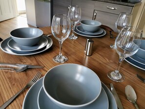 A dining table set with blue plates, clear glassware, and silverware. - 3bed Full House - Free Parking - Family Friendly! (Wolverhampton)