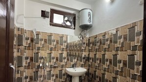 A bathroom with a white sink, a toilet, a shower, and a water heater mounted on the wall. - Snow Mount View (Dalhousie)