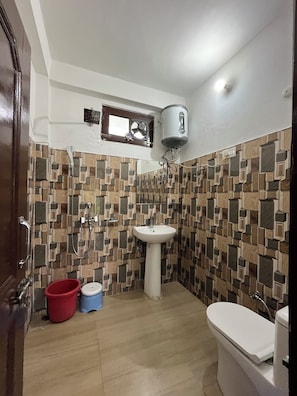 A bathroom with a white sink, a toilet, a shower, and a water heater mounted on the wall.