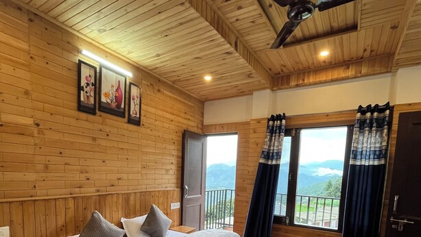 A wooden-paneled bedroom with a large bed, a ceiling fan, and a view through the window. - Snow Mount View (Dalhousie)