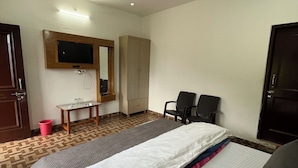 A hotel room with a bed, a desk, a chair, a television mounted on the wall, and a ceiling fan. - Snow Mount View (Dalhousie)