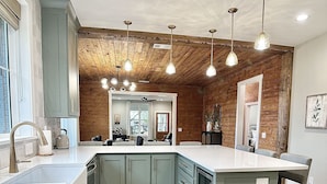 A modern kitchen with a large island, light blue cabinets, and wooden ceiling beams. - Luxury Home Near Crater of Diamonds 
3 King Beds 2 Full Baths
Sleeps 7 (Nashville)