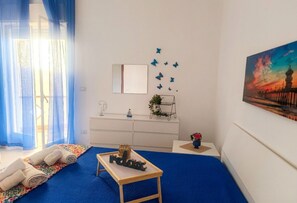 A bedroom with a bed, a bedside table, a mirror, a window with curtains, a wall-mounted plant, and a painting. - Appartamenti Abate  Conchiglia Home  (Alcamo)