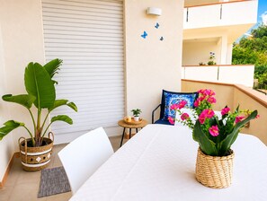 A balcony with a table, chairs, potted plants, and a view of the surrounding greenery. - Appartamenti Abate  Conchiglia Home  (Alcamo)