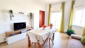 A modern living room with a TV, a dining table, and a sofa. - Appartamenti Abate  Conchiglia Home  (Alcamo)