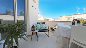 A balcony with a table, chairs, a potted plant, and a view of buildings. - Appartamenti Abate  Conchiglia Home  (Alcamo)