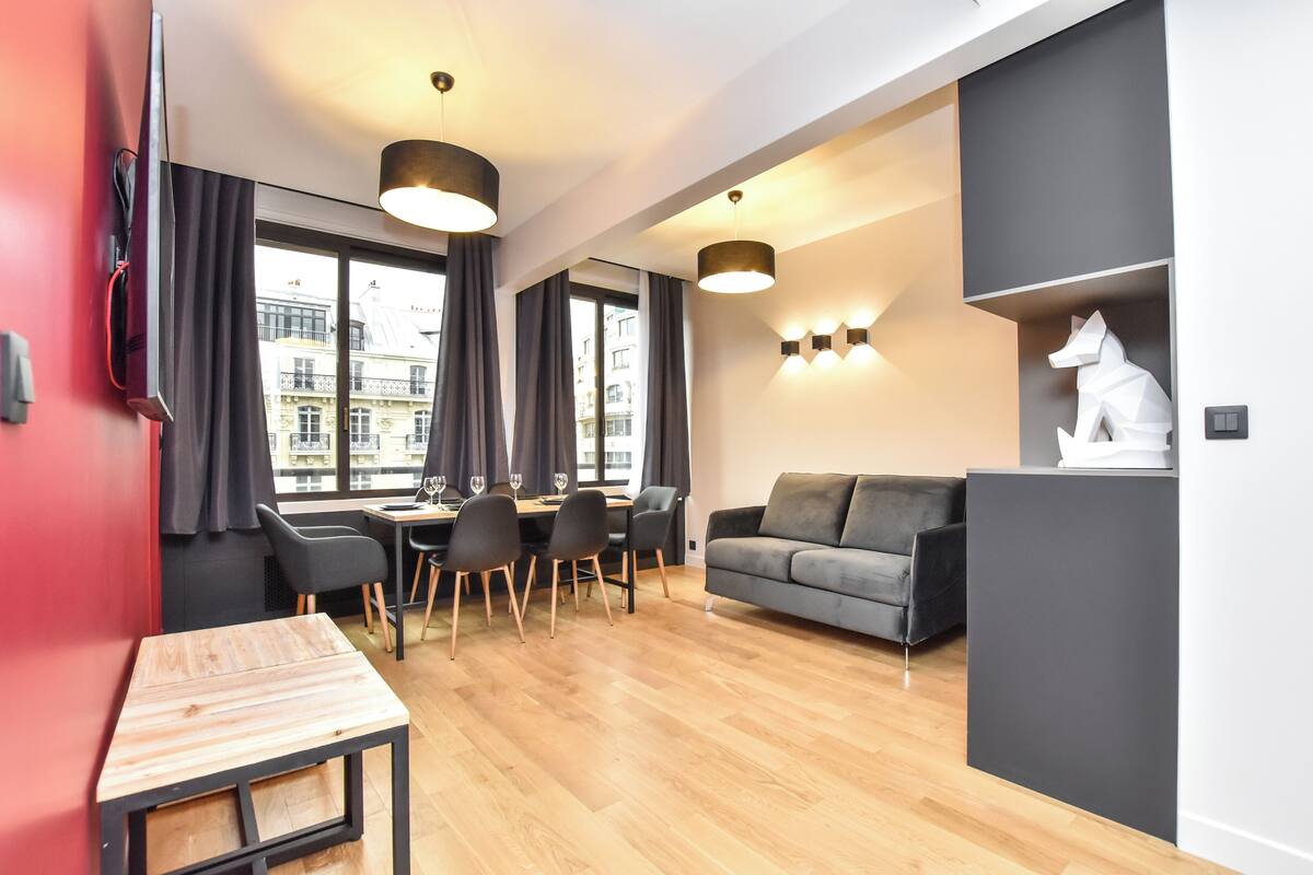 Ein modernes Wohnzimmer mit Essbereich, großen Fenstern und Blick auf die Stadt.