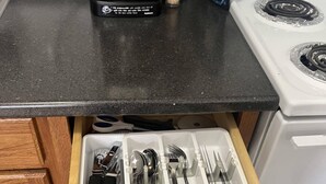 Un tiroir de cuisine contenant des ustensiles et une machine à café posée sur le plan de travail.