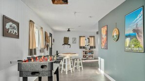 A spacious room with a foosball table, bar stools, and a kitchen area in the background. - Epic Views, Hot Tub, Pets Welcome!  Overlooking Shenandoah National Park (Stanley)