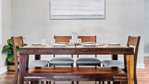 A dining table set with plates, glasses, and a centerpiece. There are four chairs around the table, and a bench at the end. - Beachy getaway in lovely Lakeland, Fl!  (Lakeland)