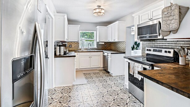 A modern kitchen with white cabinets, a stainless steel refrigerator, a microwave, and a stove. - Beachy getaway in lovely Lakeland, Fl!  (Lakeland)