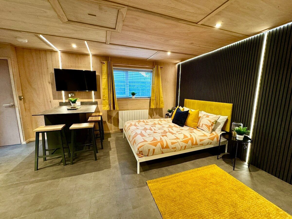 Quarto moderno com cama, escrivaninha e televisão.