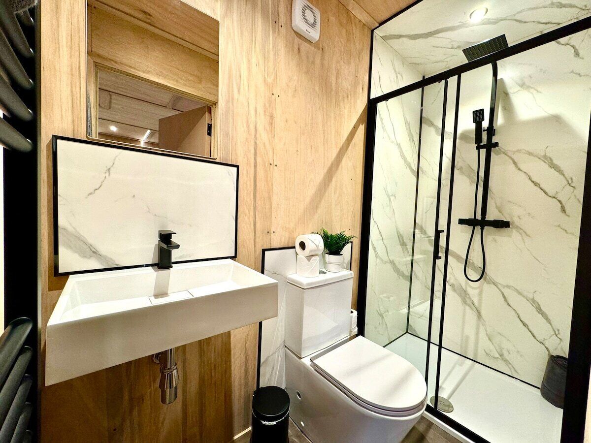 A modern bathroom with a marble sink, toilet, and glass-enclosed shower.