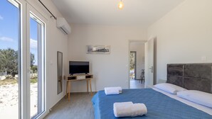 Ein Schlafzimmer mit einem großen Bett, einem Fernseher und Blick ins Freie.