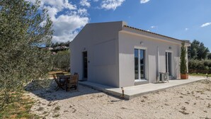Ein modernes Haus mit Terrasse, Gartenmöbeln und Kiesgrundstück.