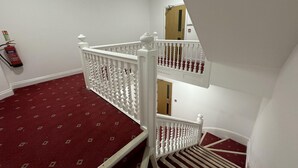 Eine Treppe mit rotem Teppich und weißen Wangen.