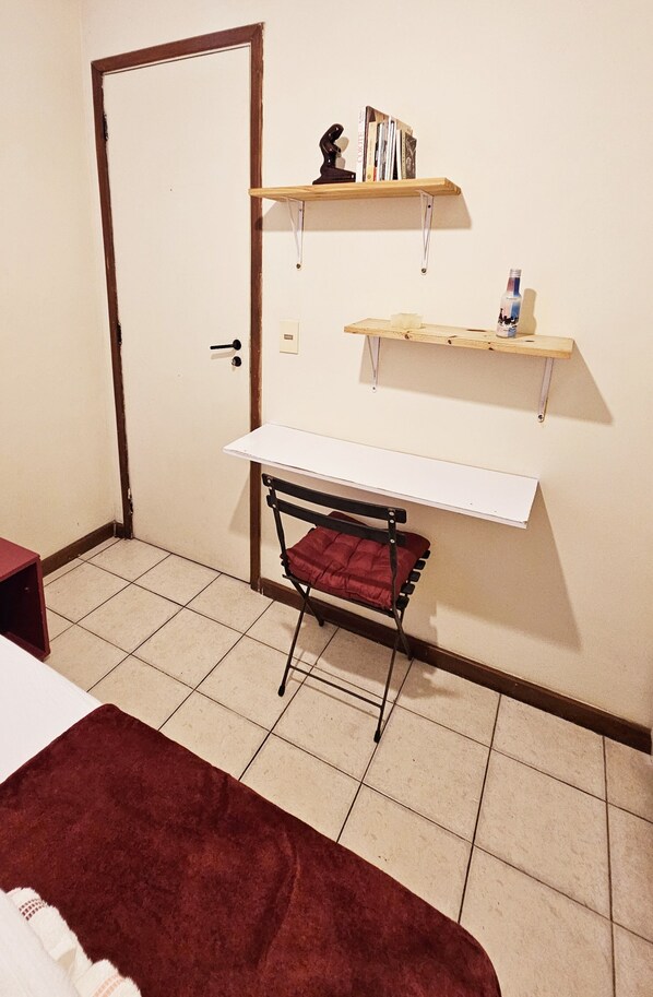 Una habitación pequeña con una cama, un escritorio y dos estanterías.