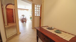A hallway with a wooden table, a lace table runner, and a door leading to another room. - Kefera's House Otranto (Otranto)