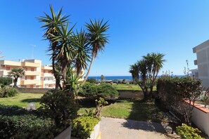 A residential area with a clear view of the sea, palm trees, and a pathway leading to a building. - Kefera's House Otranto (Otranto)