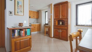 Una cocina con armarios de madera, una mesa de comedor y una estantería llena de libros.