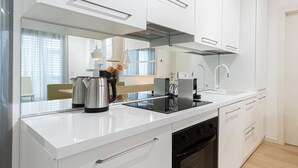 Une cuisine moderne avec des meubles blancs, une cuisinière noire et un four encastré.