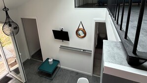 A modern interior with a skylight, a staircase, and a flat-screen TV.