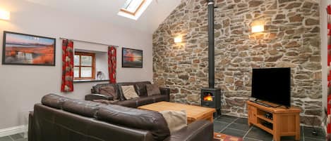 Ein gemütliches Wohnzimmer mit Steinwand, Kamin, einer Ledersofa, einem Holztisch und einem Flachbildfernseher.