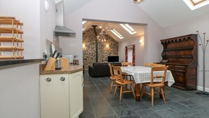 Une cuisine compacte avec un coin repas, comprenant un mur en pierre, un meuble en bois et une table dressée pour quatre personnes.