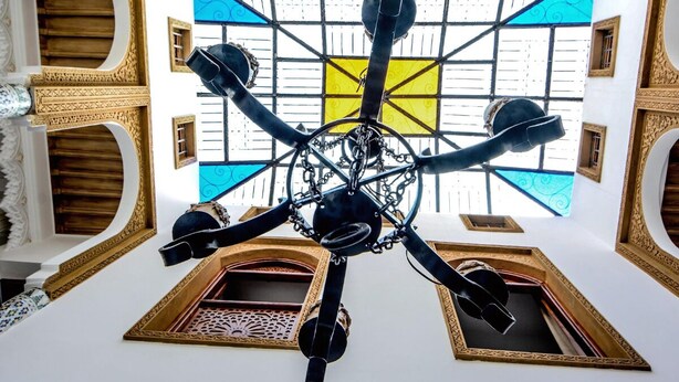 A room with a large, ornate chandelier, a patterned floor, and a view through a window with a geometric design. - RYAD RDATE LWALIDINE (Marrakech)