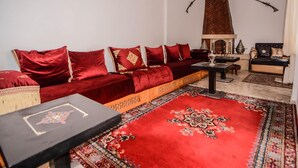 A living room with a red sofa, a wooden coffee table, and a patterned rug. - RYAD RDATE LWALIDINE (Marrakech)