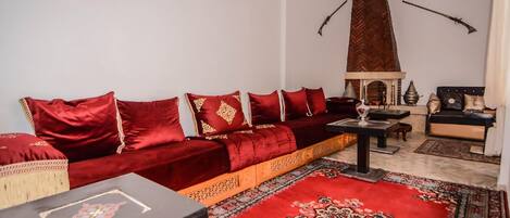 Una sala de estar con un sofá rojo, una mesa de centro de madera y un tapete estampado.