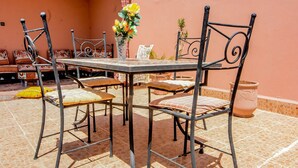 A patio with a metal table and chairs, a potted plant, and a tiled floor. - RYAD RDATE LWALIDINE (Marrakech)