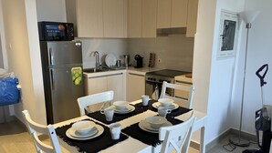 A modern kitchen with a refrigerator, stove, and microwave. There is a dining table set with plates, bowls, and cups.