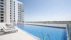 A swimming pool with lounge chairs and a high-rise building in the background.