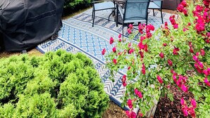 A patio with a table and chairs, a covered seating area, and a patterned floor.
