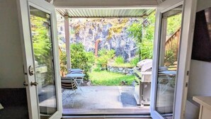 A view from inside a house to an outdoor patio with a grill and dining area. - Private Garden Suite in Langford - Free car charger (Langford)