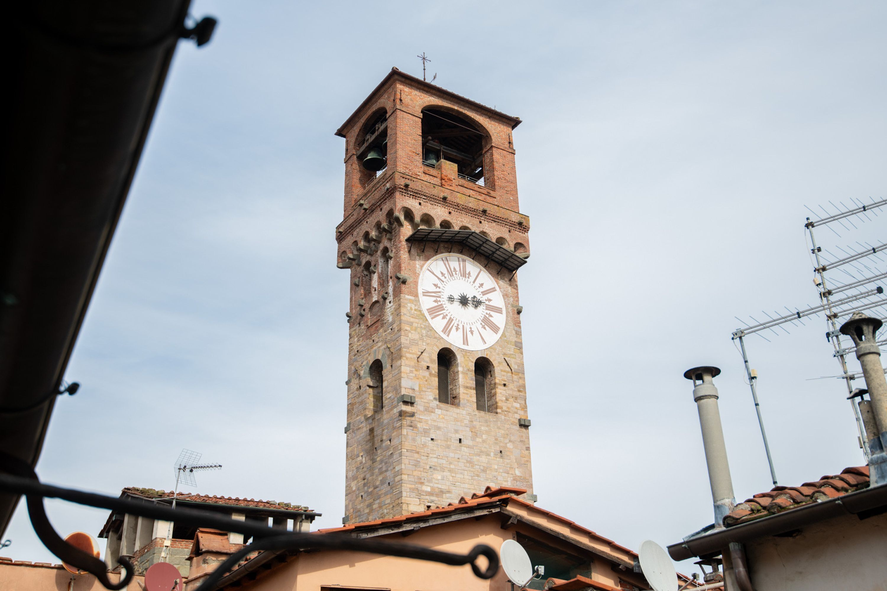Una torre de maó alta amb un rellotge, envoltada d'edificis amb antenes satèl·litz.