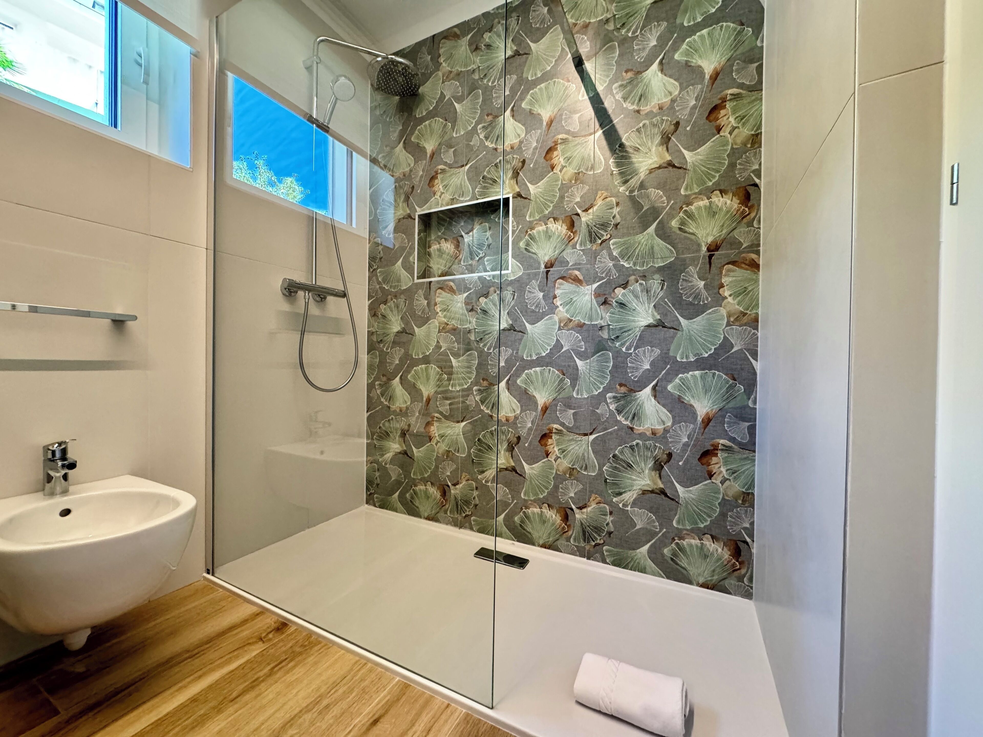 A modern bathroom with a glass shower enclosure, a sink, and a toilet.