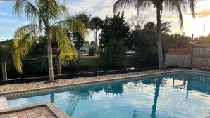 A rectangular swimming pool with clear blue water, surrounded by a brick deck and a pebble-lined border. - Canal Home with Pool near Beaches and Space Center! (Merritt Island)