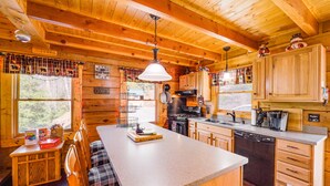 A wooden cabin interior with a kitchen, dining area, and a large window. - Cozy Family Cabin w/ Hot Tub - 10 Mi to App State! (Deep Gap)