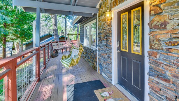 A covered porch with a stone wall, a wooden deck, and a black door with yellow accents. - Lake Access & Hot Tub: Pet-Friendly Arnold Home (Arnold)