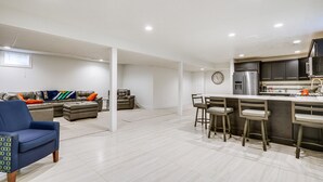 Une cuisine moderne avec un coin bar, un ensemble de salle à manger et un espace salon comprenant un canapé et des fauteuils.
