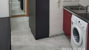 Una cocina compacta con lavadora, refrigerador y espejo.