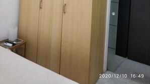 Una habitación con un armario de madera, una pequeña mesa con una impresora y una puerta de color oscuro.