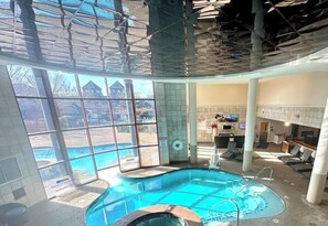An indoor swimming pool with clear glass walls, a hot tub, and a view of a building outside. - Waterfront property in Newport Rhode Island June 23-30 2024. Downtown resort. (Newport)