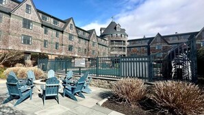 Un bâtiment en briques doté d’une tourelle et d’un espace extérieur clôturé, aménagé avec des fauteuils Adirondack.