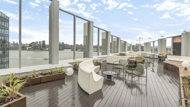 A rooftop terrace with modern seating, large windows, and a view of the city. - Stylish 1-bed Apartment in London (London)